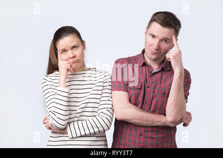 Attractive young couple standing side by side pense perplexe Banque D'Images