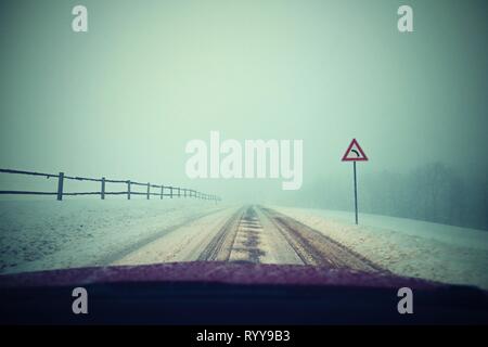 Conduire la voiture en hiver. Vue depuis l'intérieur d'une voiture sur une route enneigée par les yeux du conducteur. Concept pour la sécurité de la conduite en hiver. Banque D'Images