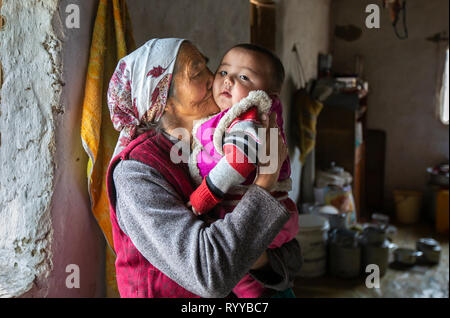 Bayan Ulgii, Mongolie, 30 Septembre 2015 : nomade kazakh mongol granmother tenant un enfant sur ses genoux à l'intérieur d'une maison d'hiver Banque D'Images