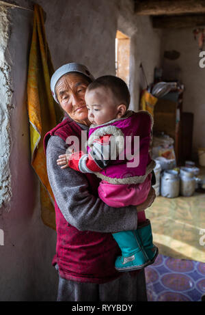 Bayan Ulgii, Mongolie, 30 Septembre 2015 : nomade kazakh mongol granmother tenant un enfant sur ses genoux à l'intérieur d'une maison d'hiver Banque D'Images
