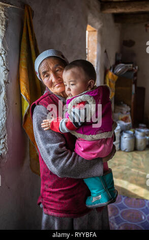 Bayan Ulgii, Mongolie, 30 Septembre 2015 : nomade kazakh mongol granmother tenant un enfant sur ses genoux à l'intérieur d'une maison d'hiver Banque D'Images