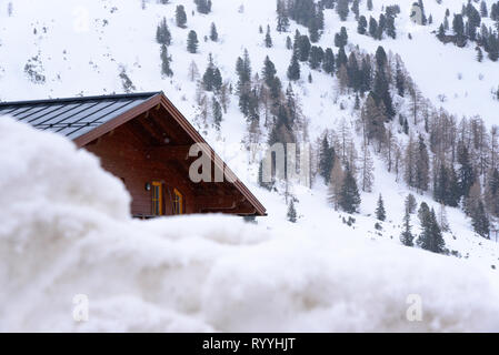 Un cottage en bois caché derrière sont abondantes dans l'arrière-plan sont les pins et les pistes de ski, chalet dans la neige, hiver en Autriche Banque D'Images