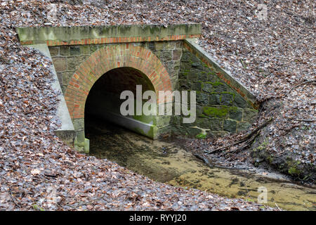 Ponceau de pierre sur la route pour une petite rivière. Un petit cours d'eau dans une zone forestière. La saison de printemps. Banque D'Images