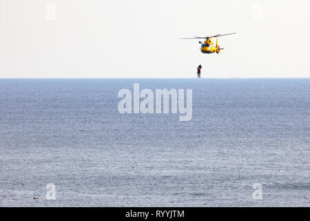 Un hélicoptère de la Dutch coastgard est la descente en rappel deux hommes sur la mer au cours d'une descente en rappel est deux hommes sur la mer au cours d'un exercice de sauvetage Banque D'Images