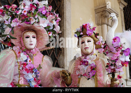 Couple dressed in costumes et masques traditionnels pour Carnaval de Venise debout sous arches à du Palais des Doges, de la Piazza San Marco, Venice, Veneto, Italie Banque D'Images