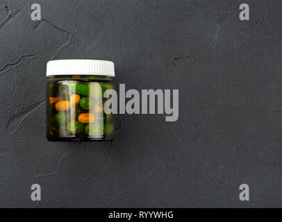 Capsules différentes dans un bocal en verre sur un fond sombre, vue du dessus Banque D'Images