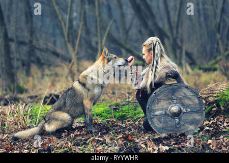 Beau guerrier viking woman warrior vêtements, avec une hache et bouclier, à côté d'un loup sauvage Banque D'Images