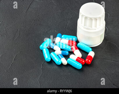 Capsules en plastique coloré avec jar sur fond sombre Banque D'Images