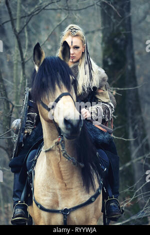 Guerrier Viking femme aux cheveux tressés et visage peint Cheval d'équitation en forêt Banque D'Images