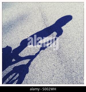 L'ombre d'un jeune enfant portant un casque tout en faisant du vélo. Banque D'Images