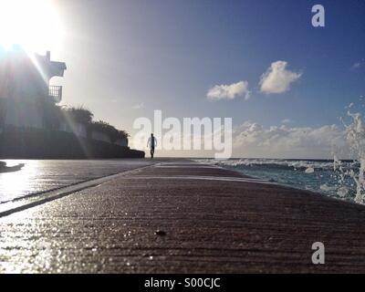 Les touristes et habitants de passer le matin sur la promenade à Accra Beach sur la côte sud de la Barbade. Banque D'Images