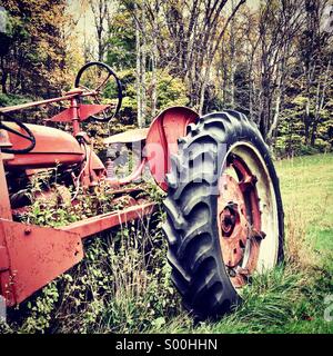 Vieux tracteur avec envahis par les mauvaises herbes. Banque D'Images