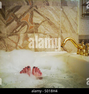 Les orteils d'une femme oeil à partir d'un bain moussant relaxant dans une baignoire de fantaisie Banque D'Images