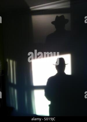 Silhouette of man in hat - fenêtre de la lumière reflétée sur le mur et le plafond des chambres d'hôtel Banque D'Images