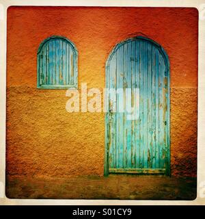 Porte bleue et fenêtre contre orange wall au Maroc. Banque D'Images