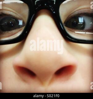 Close-up d'un visage d'enfant portant des lunettes noires. Banque D'Images