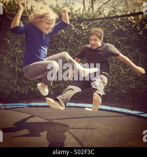 Frère et soeur sur trampoline - 8 ans et 13 Banque D'Images
