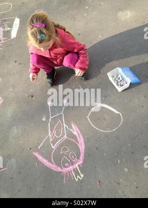 Petite fille dessin à la craie sur l'asphalte Banque D'Images