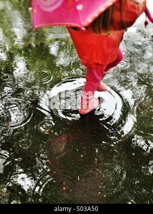 Enfant en rouge une marche sous la pluie Banque D'Images