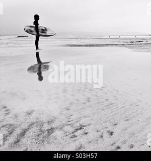 Contrôle du surfeur vagues en hiver à la première lumière. Banque D'Images