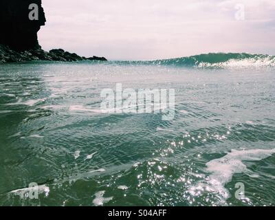 Un promontoire rocheux dans la région de Cornwall avec une vague se brisant sur une journée ensoleillée à la mer. Banque D'Images