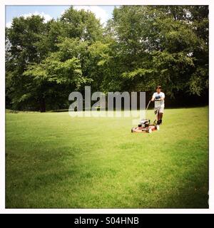 Boy cutting grass Banque D'Images