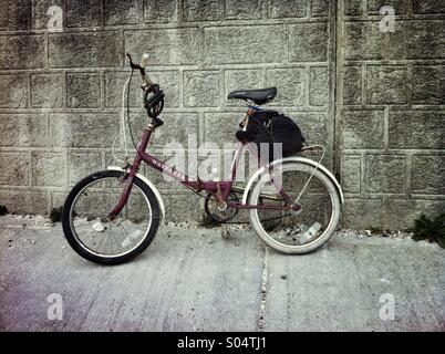 Shopping Vintage vélo avec un sac sur le dos appuyé contre le mur près de Falaise en vertu de Brighton, Angleterre. Banque D'Images