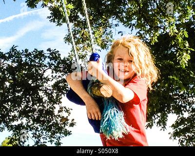 Jeune garçon sur swing fait maison dans un parc Banque D'Images