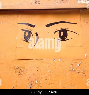 Une peinture de deux yeux décore un mur orange dans la ville de Mexico, Mexique Banque D'Images