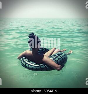 Jeune femme flottant sur un anneau de caoutchouc dans l'océan Atlantique, Algarve, Portugal Banque D'Images