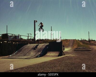 Rider BMX sautant sur un circuit dans le soleil Banque D'Images