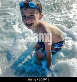 Un garçon jouant dans les vagues sur la plage de Sant Pol de Mar, el Maresme, Barcelone, Espagne Banque D'Images