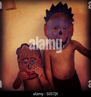 C'est une photo de deux frères qui portent des masques en carton peinture ils pour l'halloween. C'est style zombie africains Banque D'Images