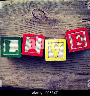 C'est une photo de quatre cubes en bois jouet avec des lettres qui forment le mot vivre Banque D'Images
