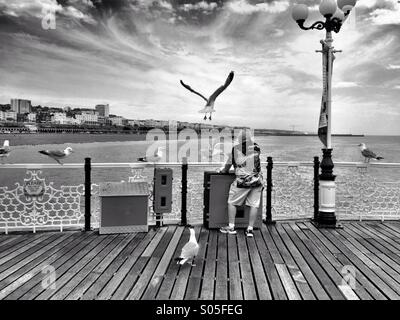 Un homme rss mouettes sur la jetée de Brighton, Angleterre, RU Banque D'Images