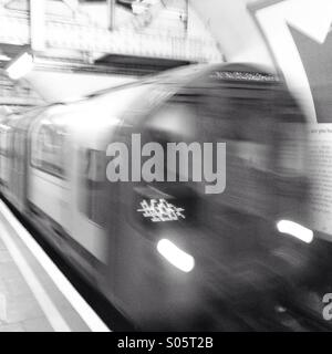 Train de tube en tirant dans une station sur le métro de Londres Banque D'Images