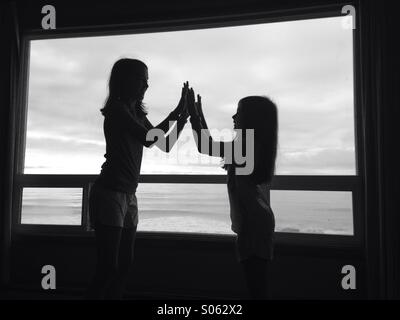 Deux filles en haute silhouette cinq en face d'une fenêtre de vue. L'image est en noir et blanc. Banque D'Images