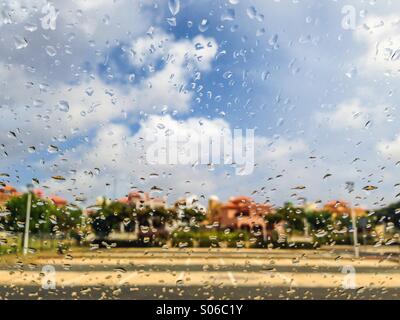 Gouttes de pluie sur un pare-brise en face de jolies maisons résidentielles. Banque D'Images