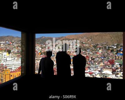 Trois personnes à plus de Guanajuato Mexique à partir d'une fenêtre du funiculaire Banque D'Images