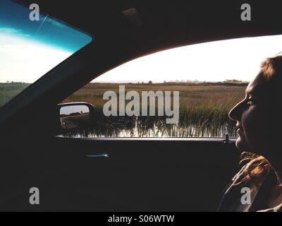 Une jeune femme dans le siège passager d'une voiture pendant un voyage à travers les régions rurales Maine, USA . Banque D'Images