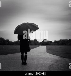 Une femme se tient dans Hyde Park un jour de pluie. Londres, Angleterre, Royaume-Uni. Banque D'Images