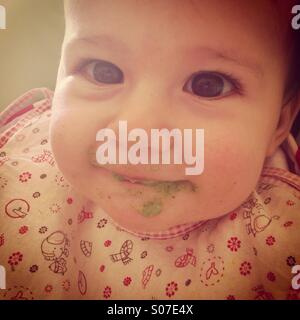 Messy baby girl eating lunch and smiling Banque D'Images