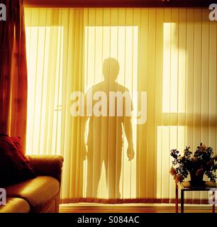 Silhouette d'ombre intimidante figure à une fenêtre représentant le risque de se casser dedans - cambriolage sécurité confidentialité vol dans Banque D'Images