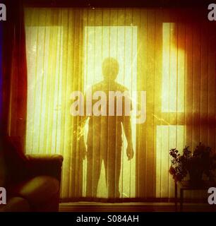 La figure menaçante de l'ombre à une fenêtre d'accueil interne - cambrioleur stalker silhouette Banque D'Images