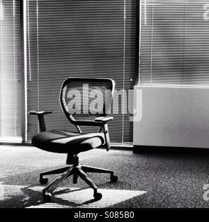 Noir et blanc à contraste élevé chaise de bureau en face de stores rétroéclairé Banque D'Images