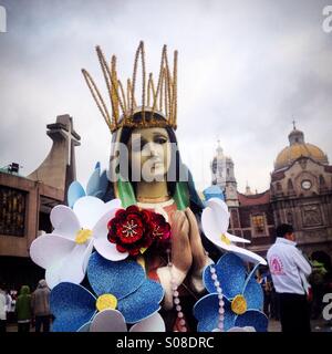 Une image de la Vierge de Guadalupe décoré de fleurs en plastique se tient sur le sol pendant le pèlerinage à la Basilique de Notre Dame de Guadalupe Tepeyac, Hill, Mexico, Mexique Banque D'Images