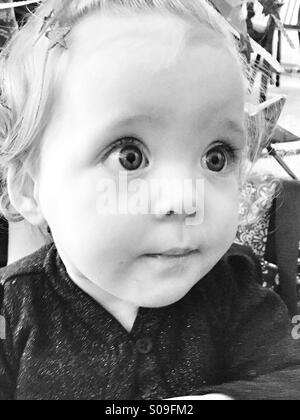 11 mois un large-eyed baby girl portrait en noir et blanc. Banque D'Images