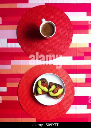 Petit-déjeuner Végétalien sur nappe géométrique rouge avec du café et des sandwichs ouverts Banque D'Images