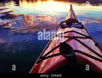 Coucher du soleil se reflète dans l'eau de mer et la proue de kayak de mer rouge Banque D'Images