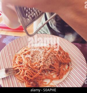 Râper le parmesan sur l'homme des pâtes avec sauce tomate Banque D'Images